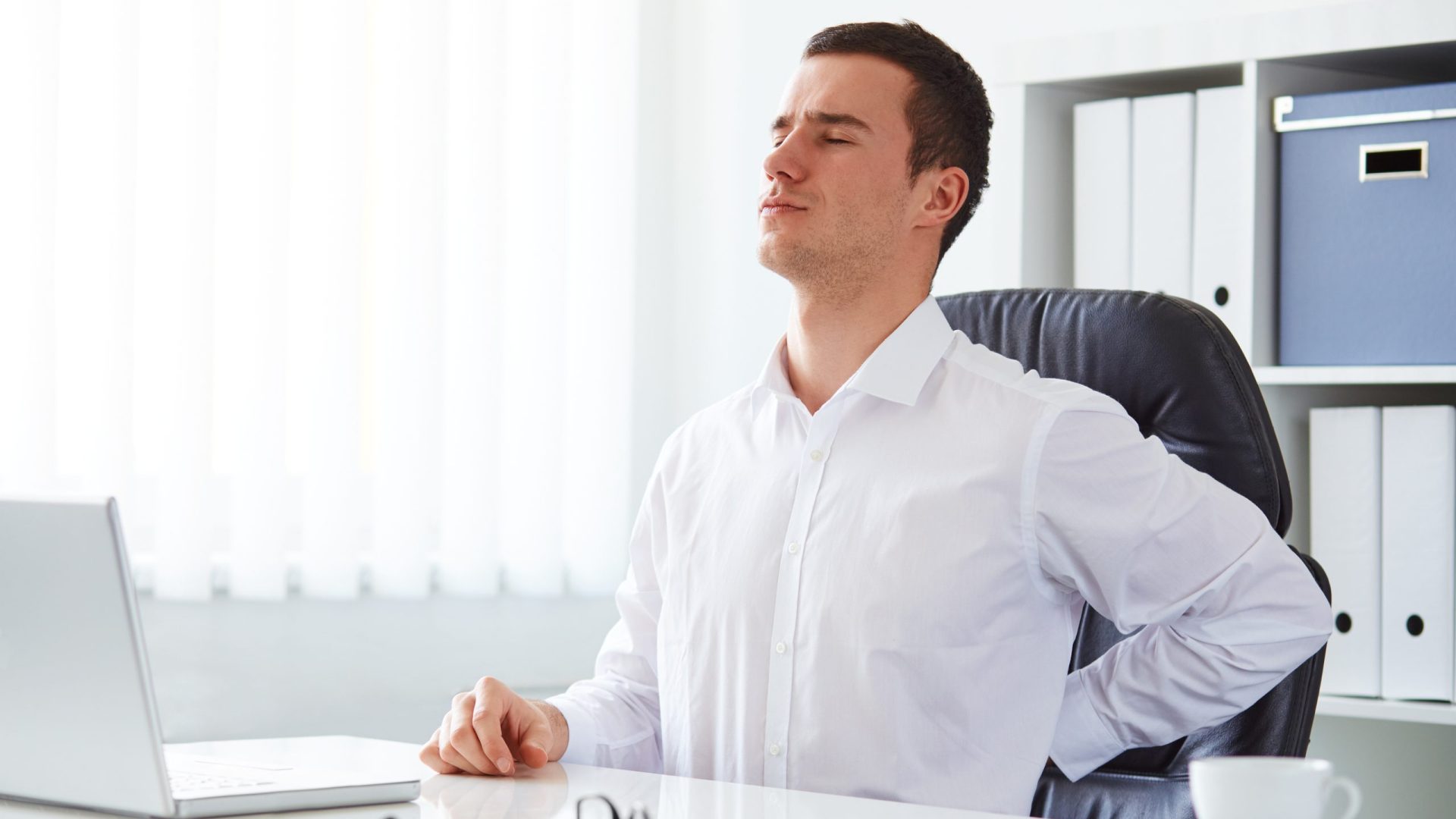 Young businessman has backache at work with a laptop